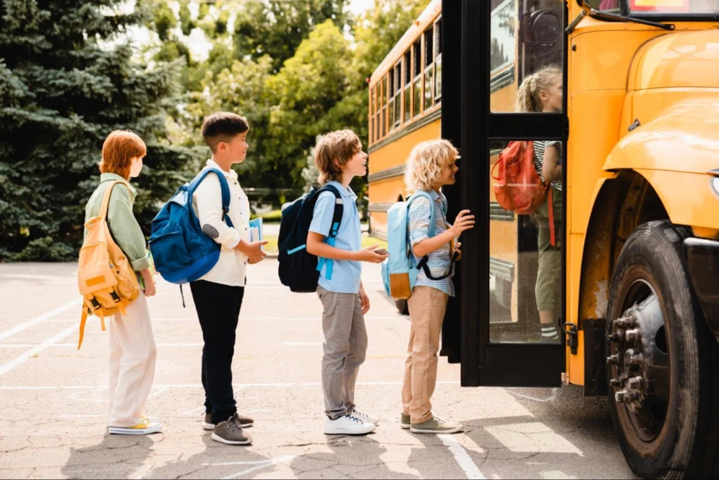 Ensuring school bus safety with school security guard services – American Security Force Children boarding a yellow school bus in a safe and orderly line, emphasizing the role of school security guard services in protecting students during transportation – American Security Force.