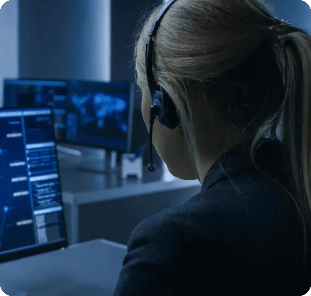 Security specialist monitoring live feeds and coordinating responses in a professional security response center.