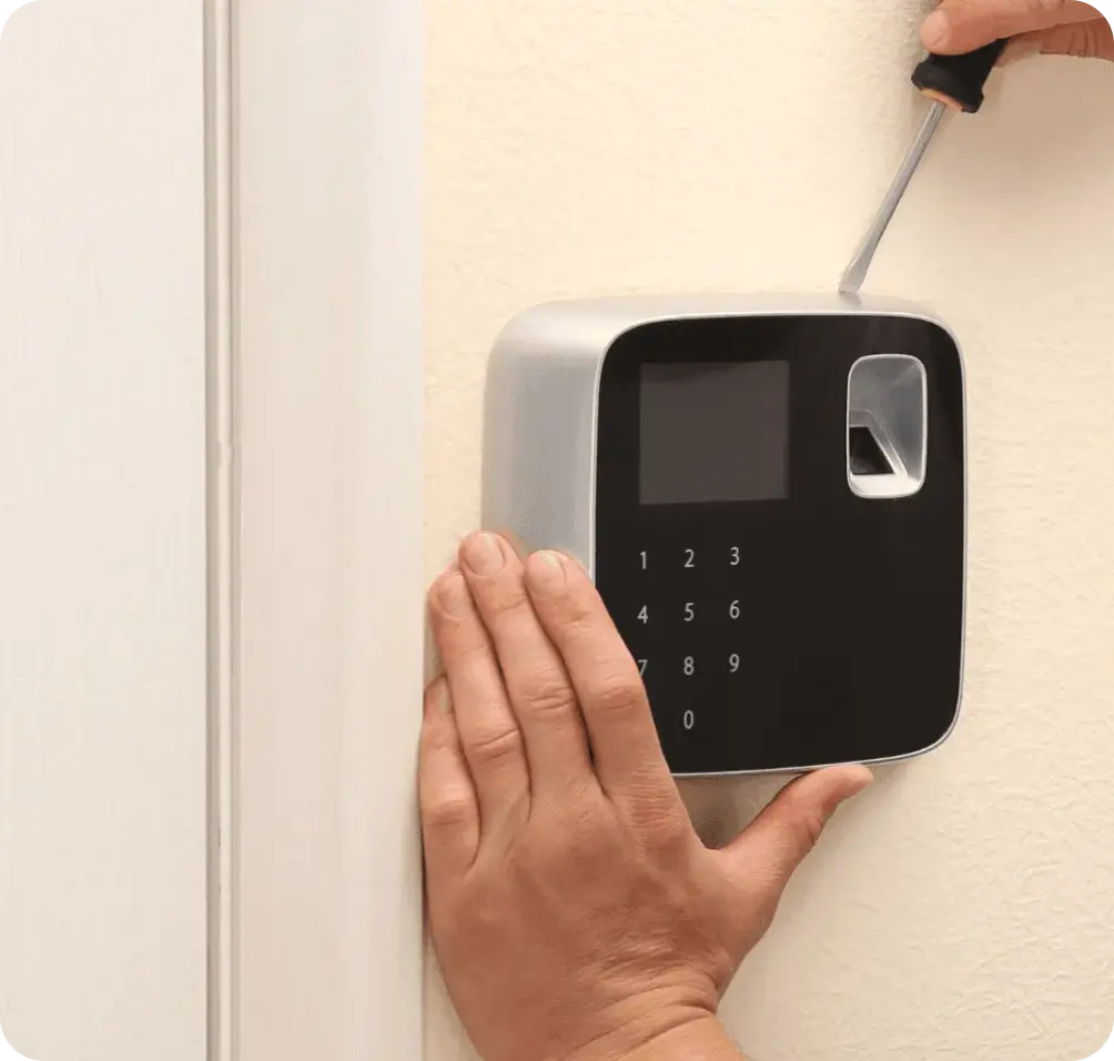 Technician installing a biometric electronic access control system on a wall.