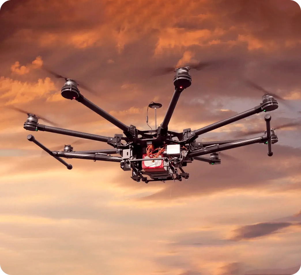 A professional-grade autonomous octocopter drone in flight against a vibrant sunset sky, built for precise navigation and automated returns to a drone docking station.
