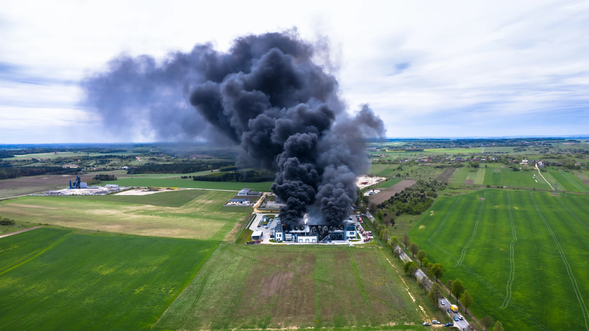 Aerial view of a warehouse fire with smoke, highlighting warehouse security and fire prevention lessons.