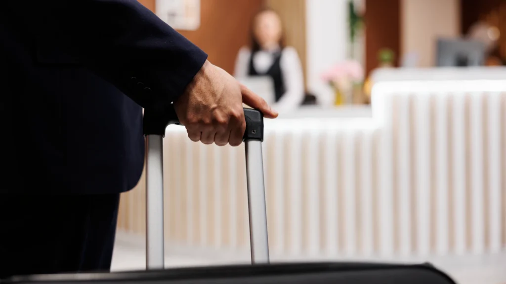 A close-up shot of a man holding a suitcase handle in a hotel lobby